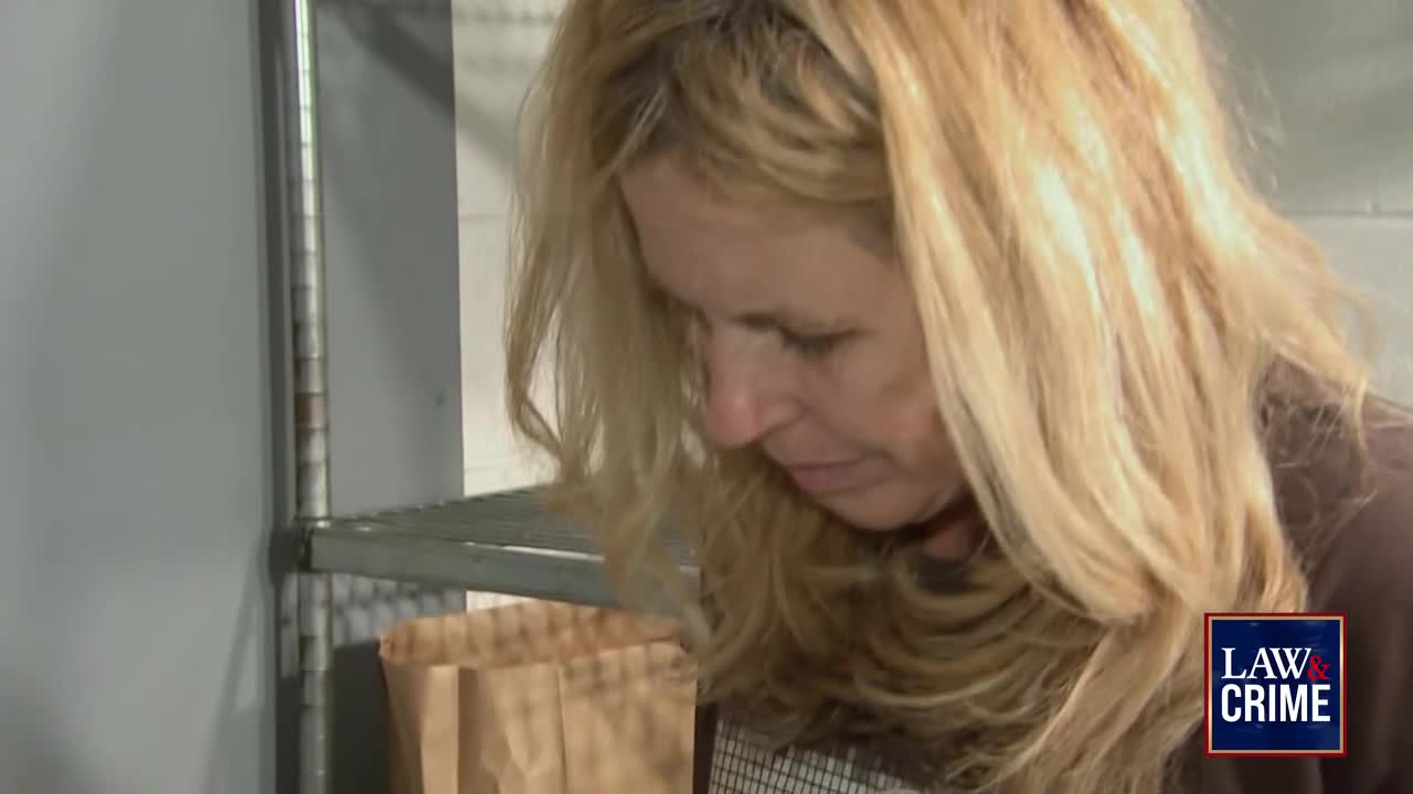 A woman with long blonde hair is looking down, her face partially obscured. The Law & Crime logo sits in the bottom right corner.
