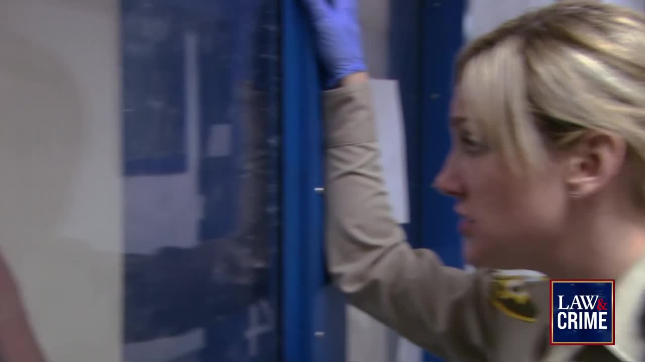 A woman in a uniform, wearing a blue glove, is reaching toward a blue door. The Law & Crime logo is visible in the corner.
