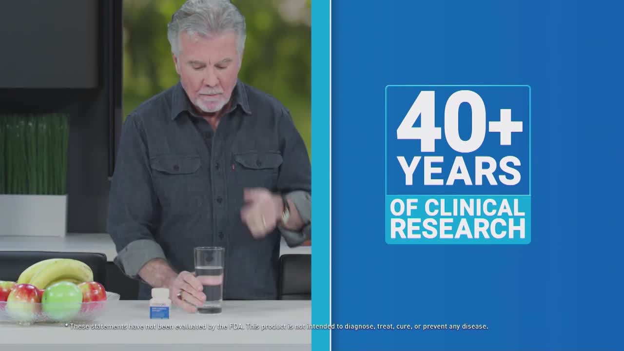 A man in a dark shirt holds a pill, about to take it with a glass of water. A blue graphic advertises "40+ YEARS OF CLINICAL RESEARCH" on the right side of the screen.
