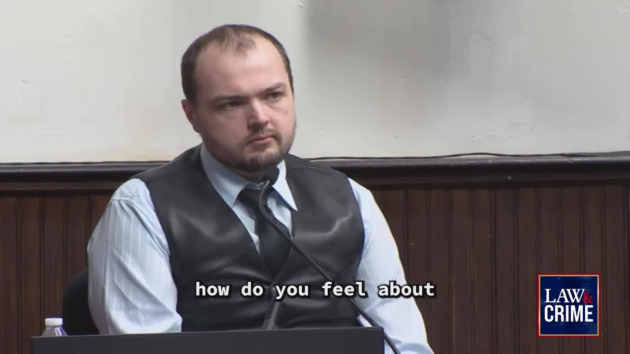 A man in a dark vest and striped shirt sits at a table, speaking into a microphone. Text on the screen reads, "how do you feel about," and a "LAW & CRIME" logo appears in the corner.
