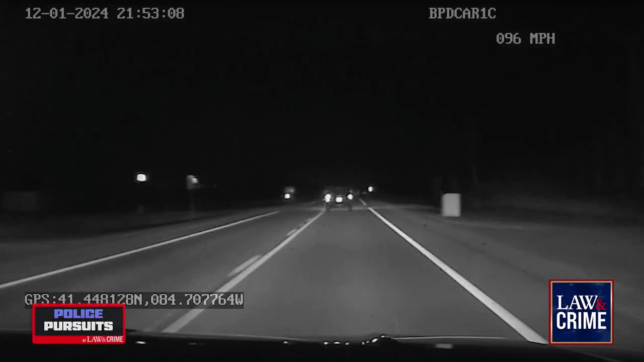 Headlights cut through the darkness as two vehicles race down a highway, the speedometer climbing to 96 MPH. The pursuit continues under a starless sky, the asphalt a ribbon of white lines ahead.