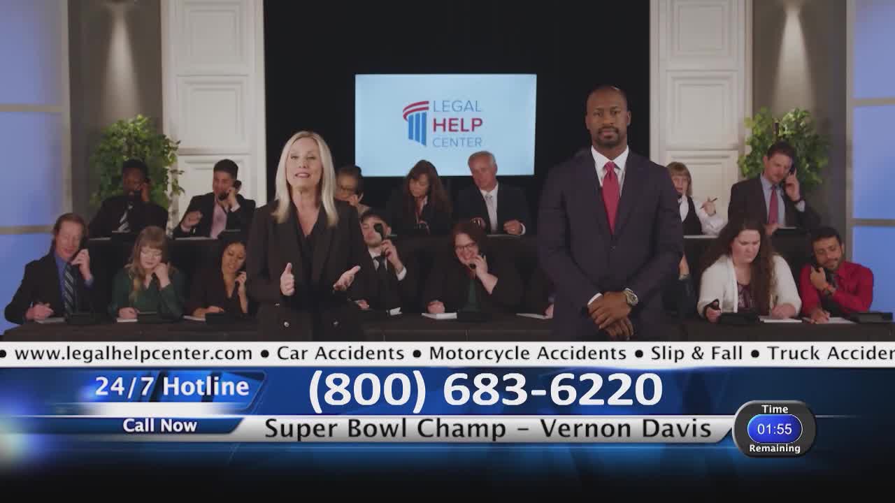 A woman in a black blazer gestures as she speaks, while a man in a dark suit stands beside her. Behind them, several people sit at desks, each with a phone to their ear. A graphic displays "Legal Help Center" and a phone number.