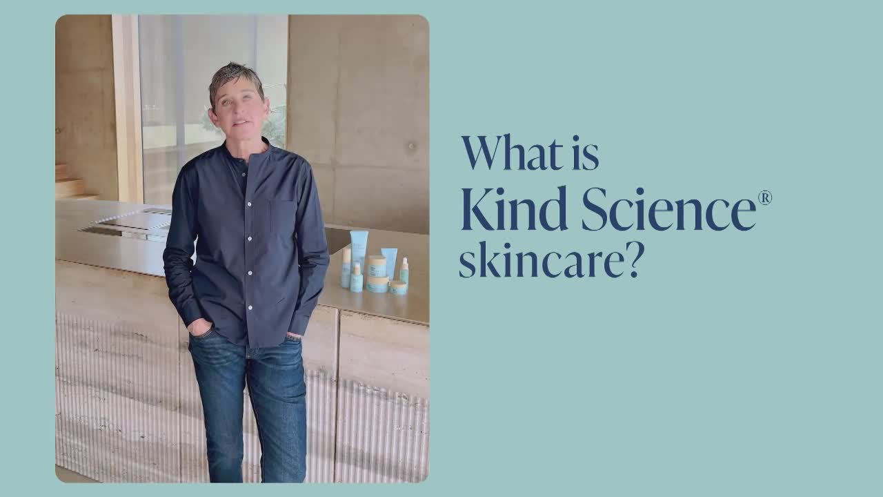 A person stands with hands in pockets, looking directly forward. Bottles of skincare products sit on a counter behind them.