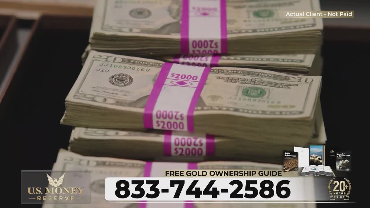 Stacks of twenty-dollar bills, bound with pink bands, rise in neat piles. A phone number and the U.S. Money Reserve logo are superimposed over the cash.