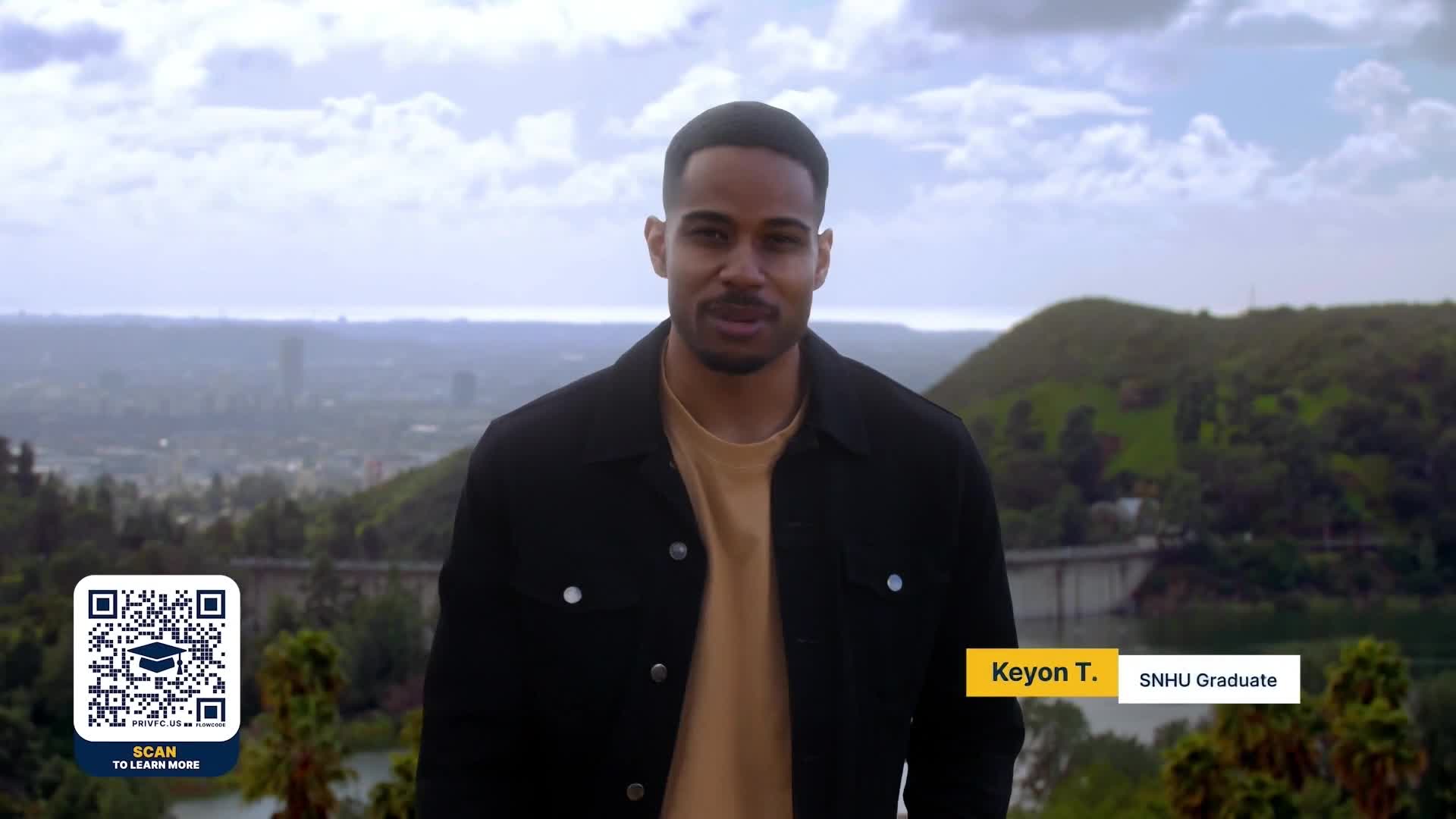A man in a black jacket stands in front of a scenic background.  A graphic identifies him as a college graduate.
