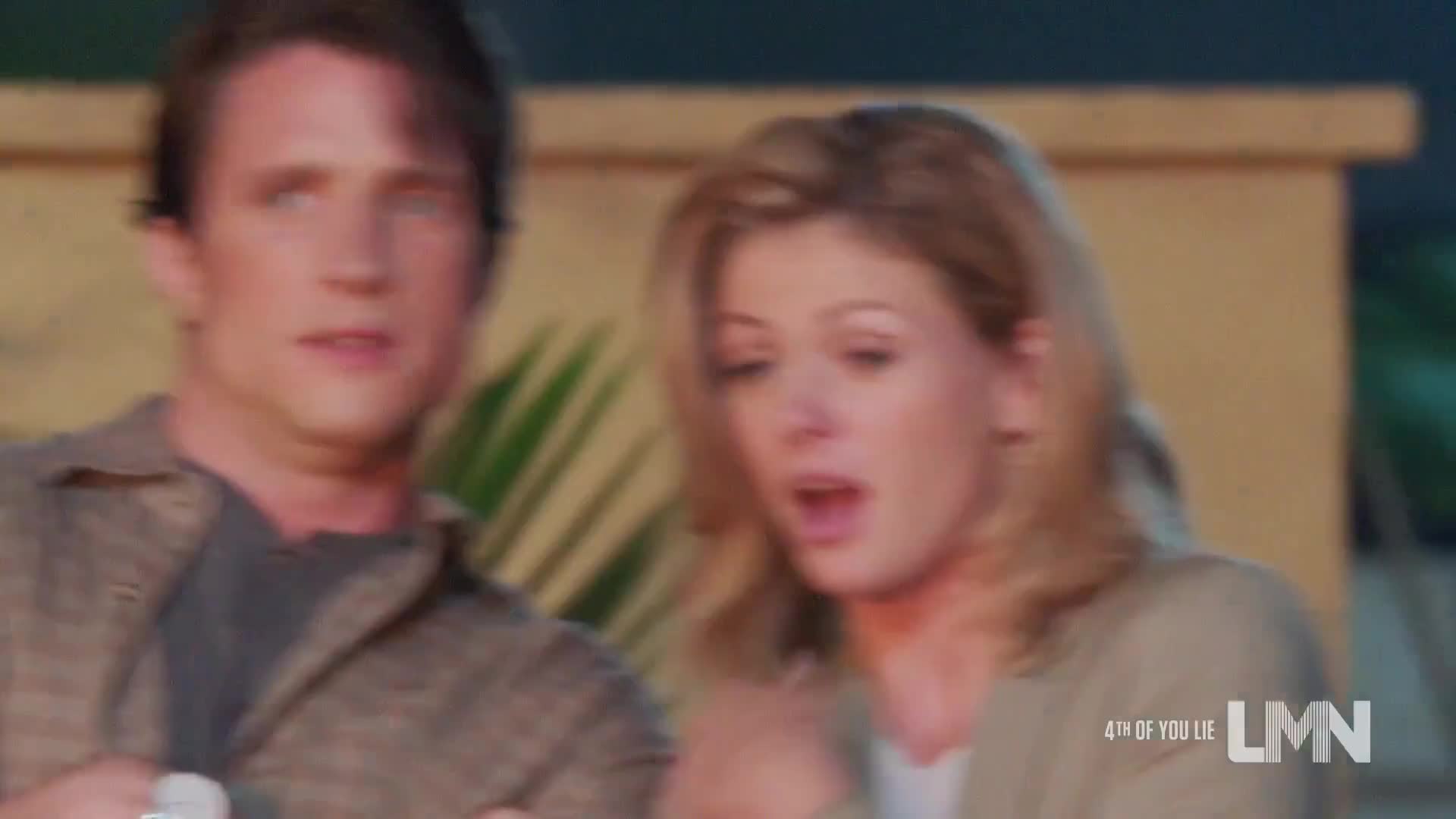 A man and woman are looking off-screen with expressions of surprise. The woman's mouth is open, and the man's eyes are wide.
