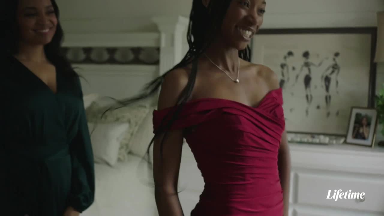 A woman in a red, off-the-shoulder dress laughs, her long braids whipping slightly.  Beside her, another woman in a dark green dress smiles, while a Lifetime logo appears in the corner.
