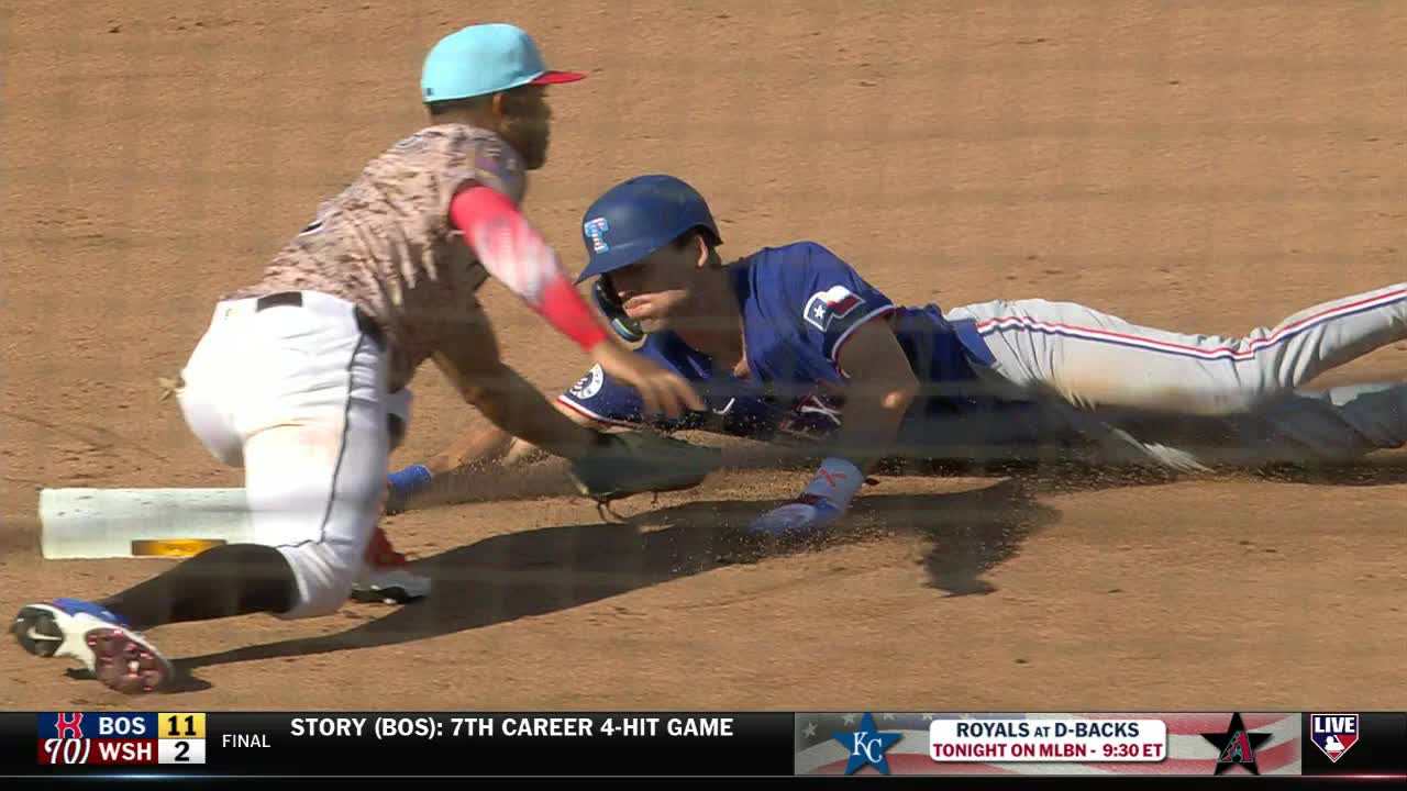 The runner is sliding headfirst toward the base, kicking up a cloud of dirt. The fielder is reaching out, glove extended, trying to make the tag.
