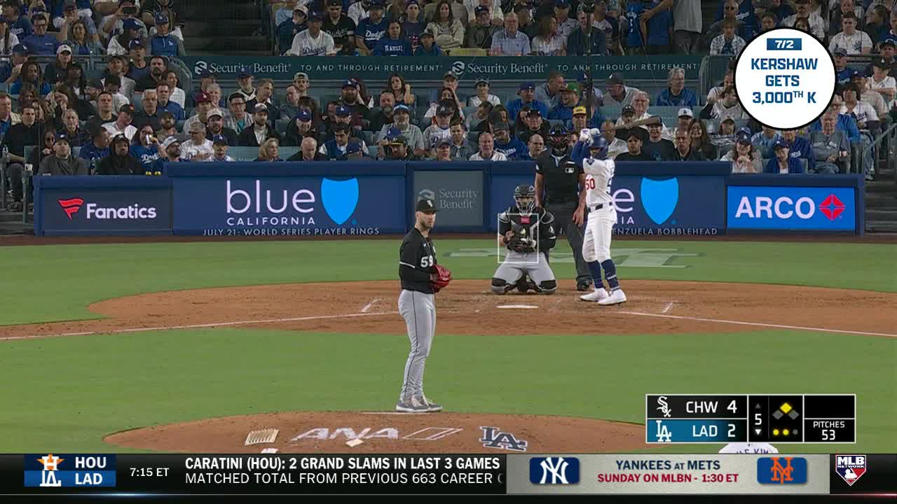 The pitcher, wearing a black and white uniform, is focused on the batter. The catcher is crouched, ready to receive the pitch as the batter stands poised at the plate.
