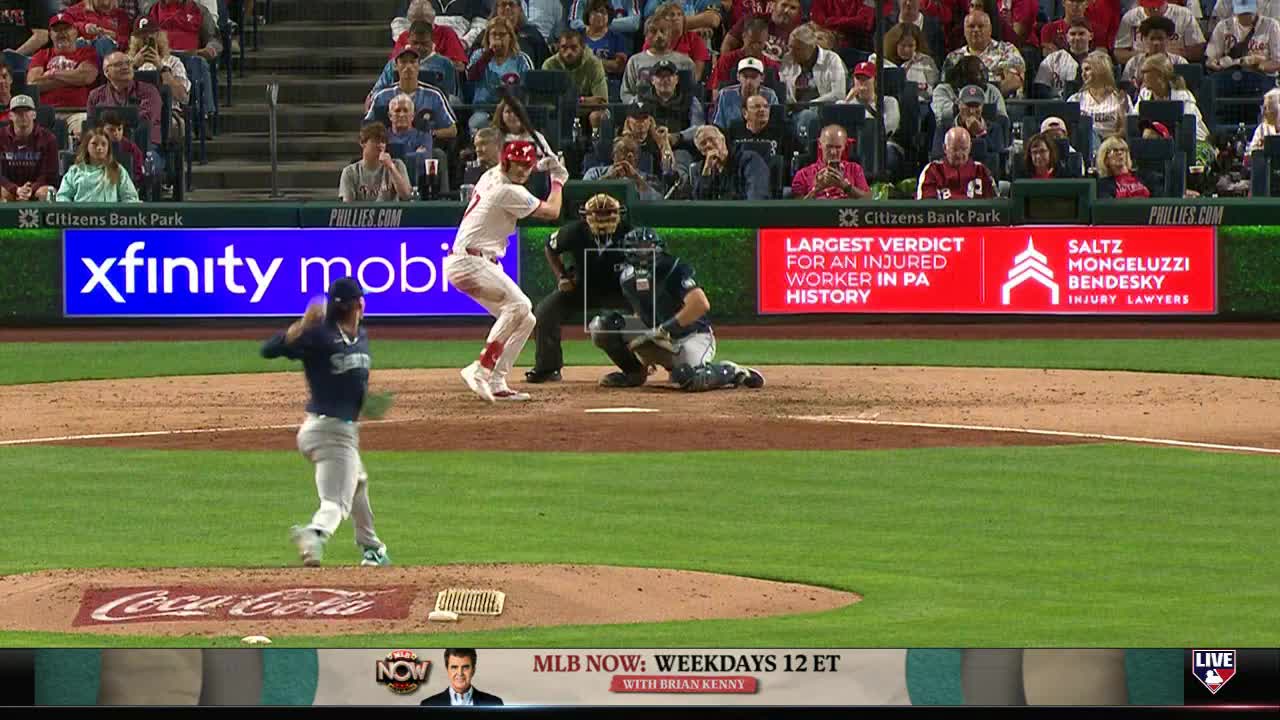The pitcher in the Mariners uniform is mid-windup, arm extended. The Phillies batter is poised, bat held high, ready to swing.
