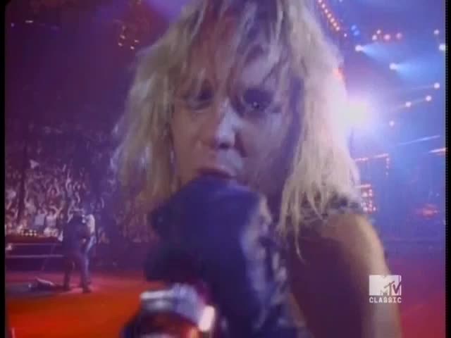 Blonde hair whips as the singer leans into the microphone, the crowd a sea of faces in the background. The MTV Classic logo glows in the corner, a reminder of the era.
