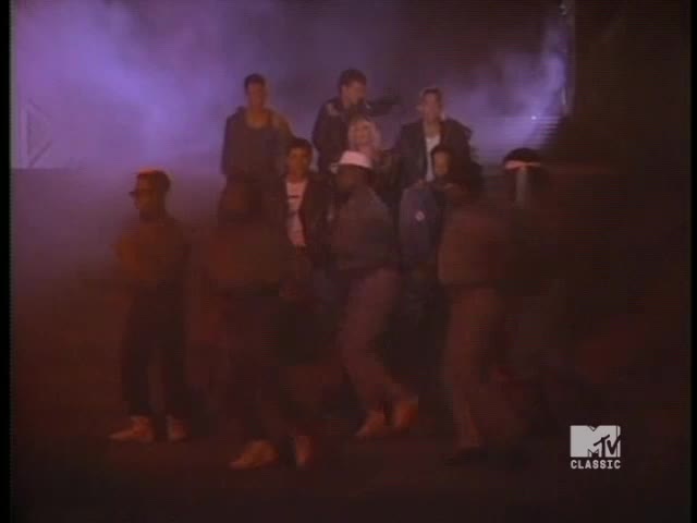 A group of guys in casual clothes are on a dimly lit stage, some standing still while others move with a quick rhythm. The MTV Classic logo in the corner is a reminder of the era.
