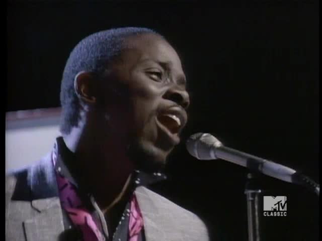 The singer's mouth is wide open, and he's belting into the microphone. His jacket has a pink and black pattern, and the MTV Classic logo is visible in the corner.
