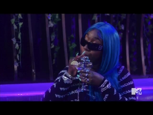 A woman with bright blue hair and sunglasses is taking a drink from a glass. The MTV Classic logo is visible in the corner.
