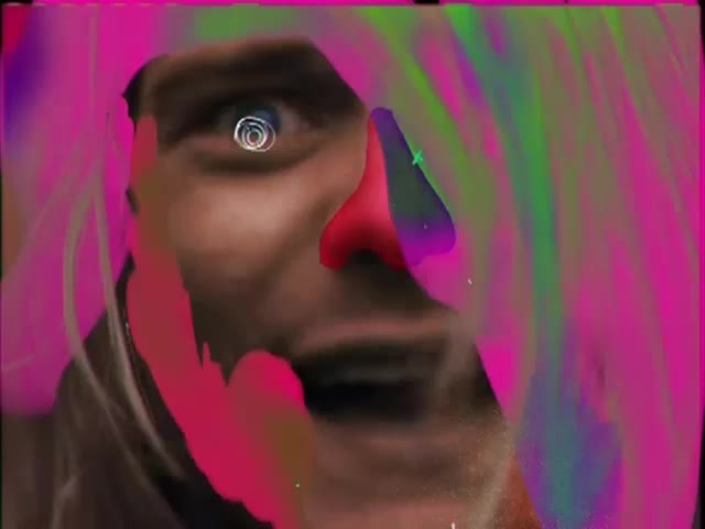 A face, painted with bright pink and green streaks, stares directly at me. The eye is wide, and a red nose sits on the face.
