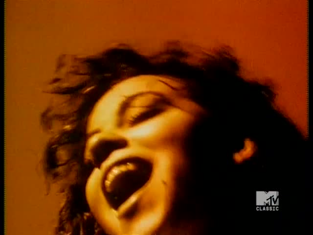 A woman's face is lit from below, her mouth wide open as she sings. Her hair is a dark silhouette against the warm, amber background, and the MTV Classic logo is in the corner.
