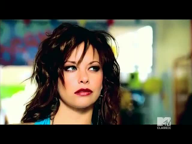 The woman with dark hair and red lipstick looks off to the side, her eyes catching the light. An MTV Classic logo appears in the corner, suggesting the scene is part of a music video from the United States.
