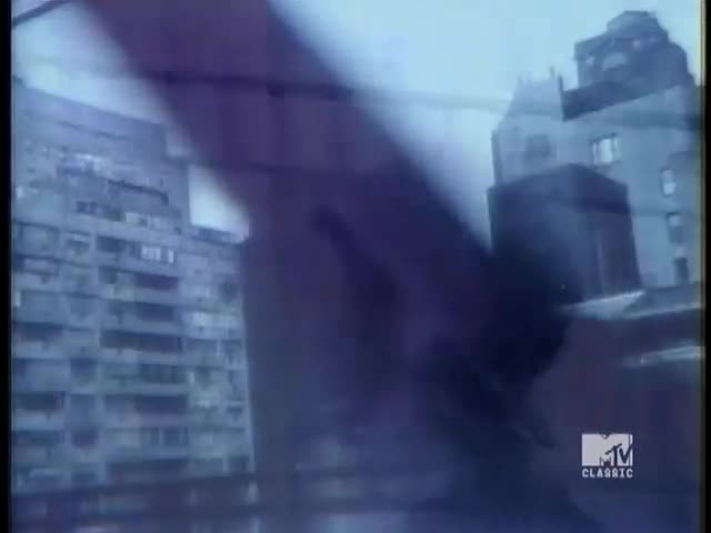 A layered cityscape, the buildings are partially obscured by a dark, blurred foreground. The MTV Classic logo is visible in the lower right corner.
