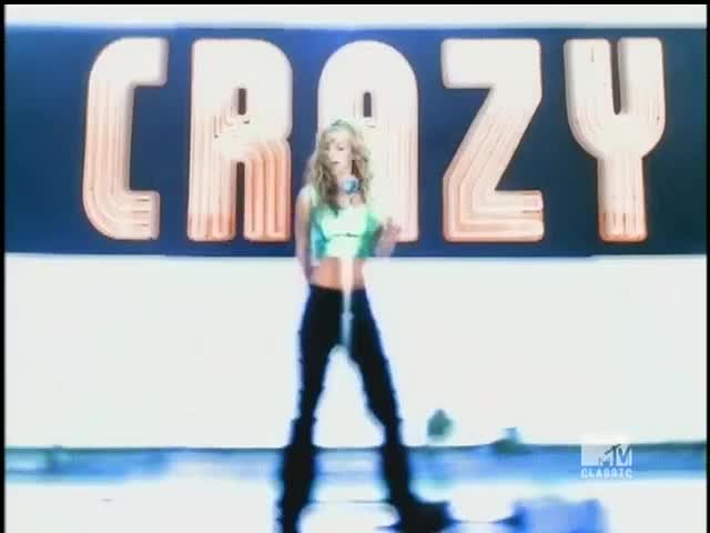 A woman in a green top and black pants dances in front of a large "CRAZY" sign. The MTV Classic logo is visible in the corner.
