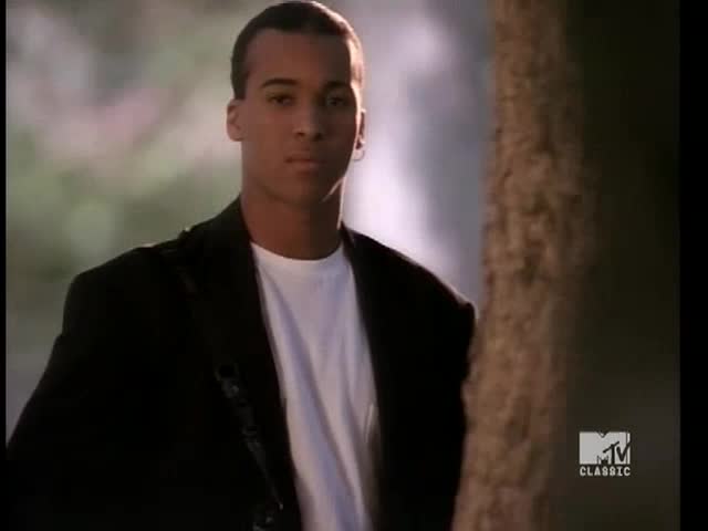 A man in a black blazer and white tee stands beside a tree, looking directly at the camera. The MTV Classic logo is visible in the corner.
