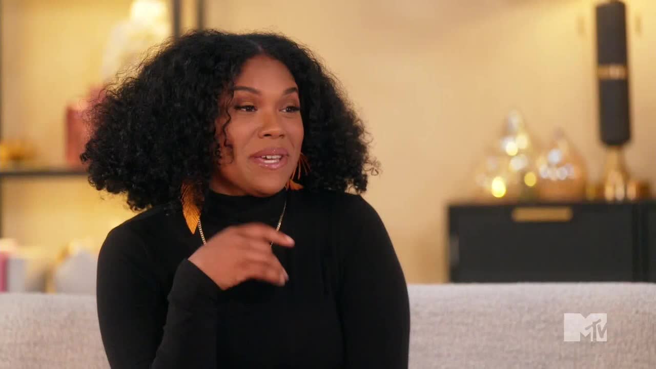 She's gesturing with her right hand as she speaks, her curly hair framing her face. The MTV Live logo sits in the bottom right corner.
