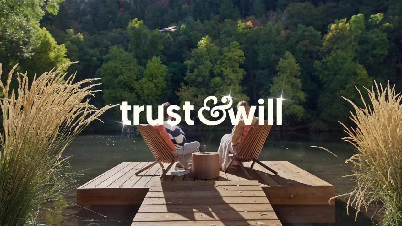 Two people sit in wooden chairs on a dock, facing the water. The words "trust & will" are emblazoned across the scene, with tall grasses framing the edge.
