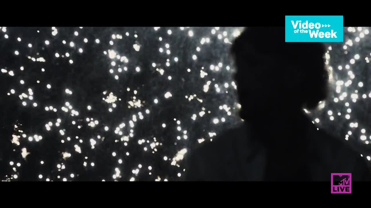A figure stands in silhouette against a backdrop of shimmering lights. The MTV Live logo is visible, and the "Video of the Week" banner is above.
