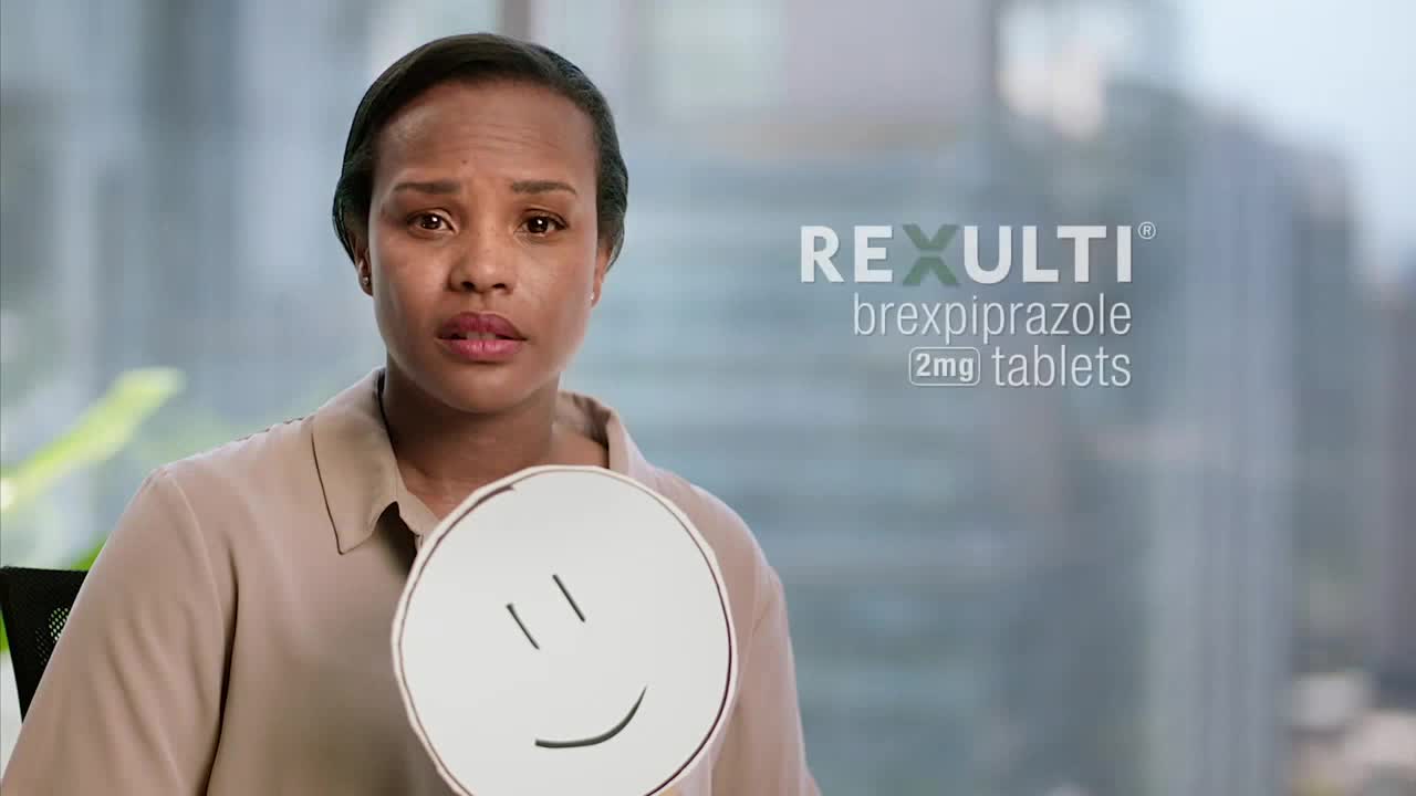 A woman with a concerned expression holds a smiley face cutout. The advertisement for Rexulti, a medication, is displayed beside her.
