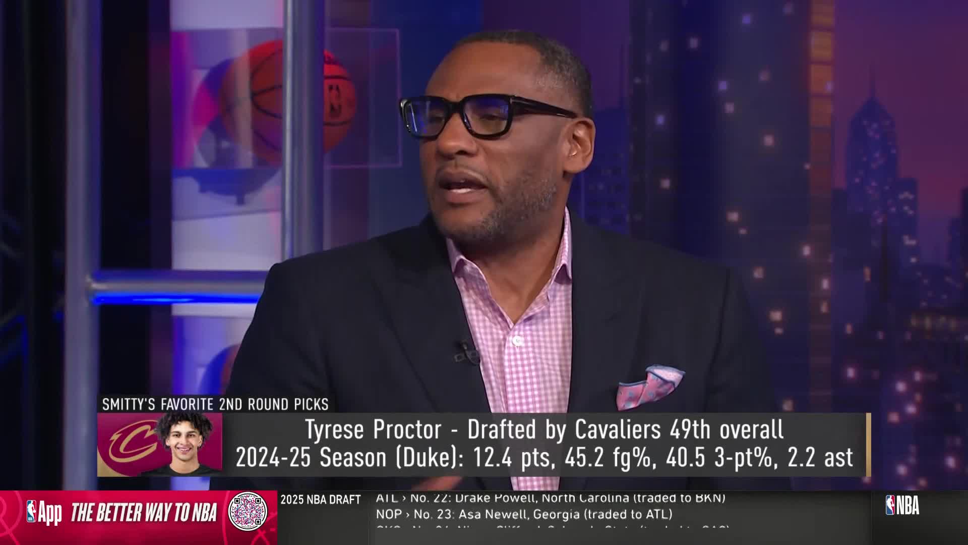 A man in a suit and glasses is speaking on NBA TV, his face illuminated by studio lights. A graphic displays player stats and team information below him.
