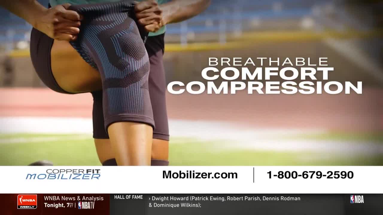 A person is pulling up a dark blue and black knee brace, the fabric stretched taut over their leg. The ad for Copper Fit Mobilizer is playing on NBA TV.

