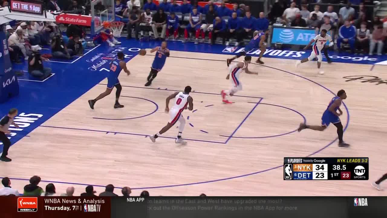 The Knicks player in blue sprints towards the basket, ball in hand, while a Pistons player in white chases him. The score is visible on the screen: New York leads Detroit.
