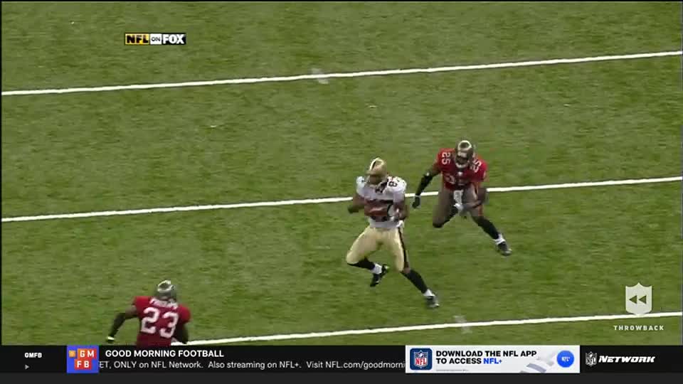 A player in gold and white sprints down the field, the ball tucked securely in his arms. Two defenders in red jerseys pursue him, trying to close the gap.
