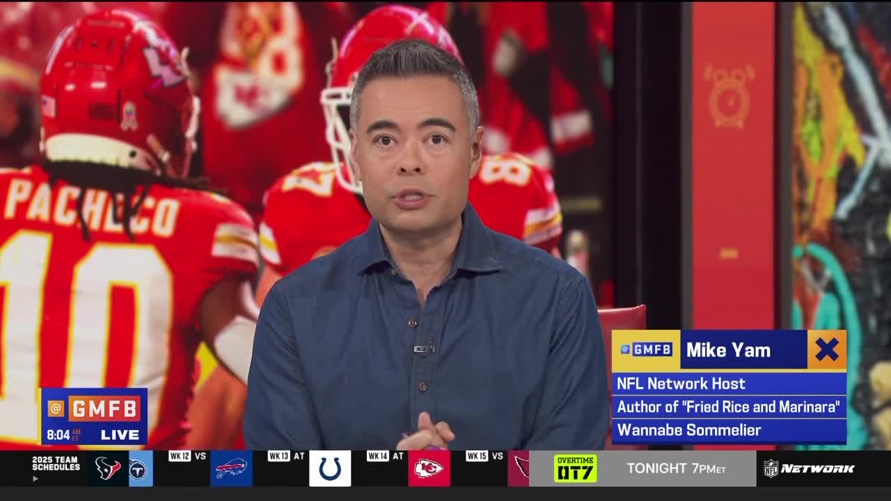 A man in a blue shirt speaks directly to the camera, with the backs of football players in red jerseys visible behind him. The NFL Network logo and Mike Yam's name are displayed on the screen.
