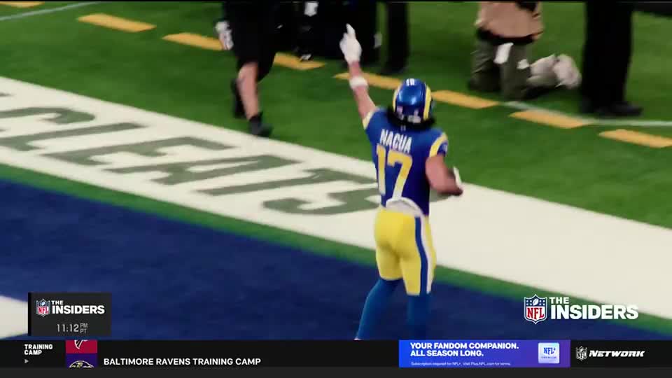 A player in a blue and yellow uniform, number 17, raises his right arm toward the end zone. He's turned to face the field, celebrating a score.
