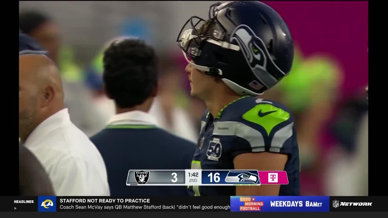 A Seattle Seahawks player, helmeted, looks toward the field. The score graphic shows the Seahawks up by 13 points in the second quarter.
