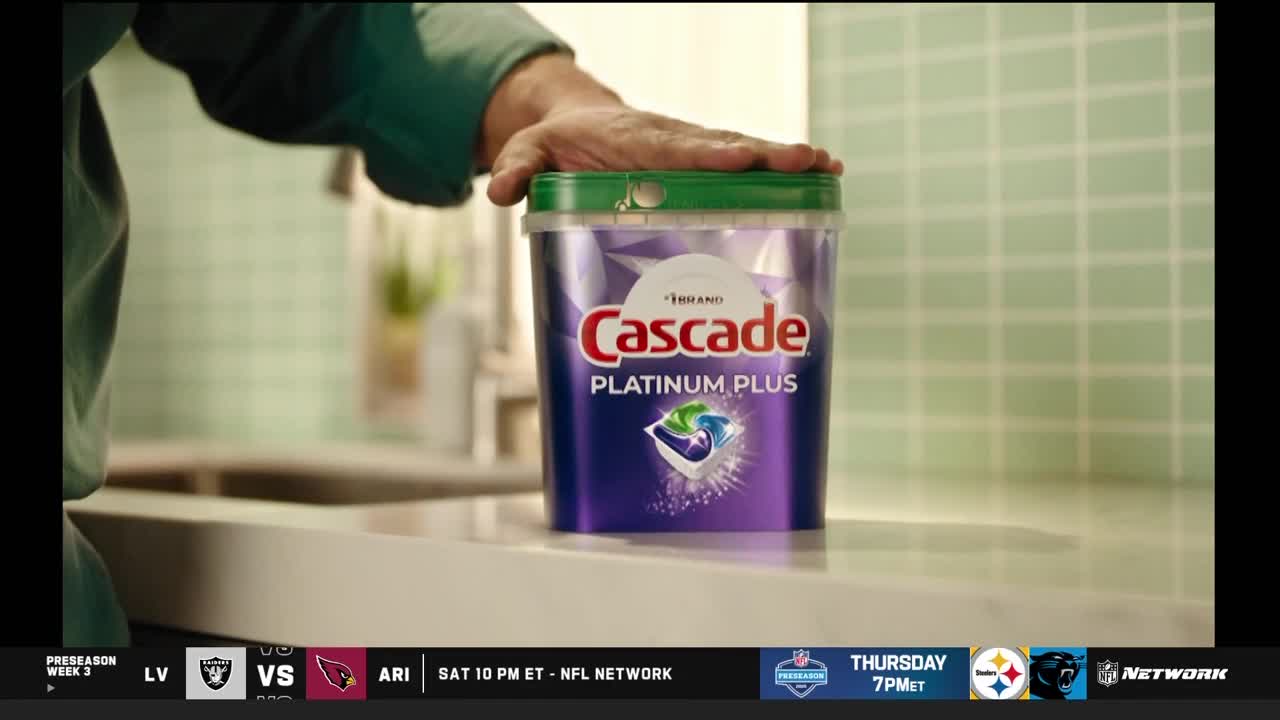 A hand rests on top of a purple Cascade Platinum Plus container. The ad is playing during an NFL Network broadcast, with a game between the Raiders and Cardinals scheduled for Saturday.
