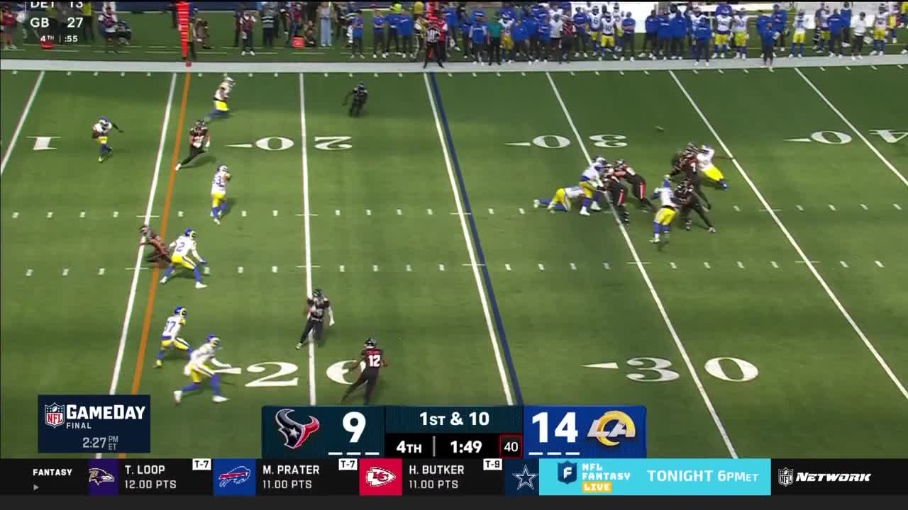The quarterback is dropping back, scanning the field as the offensive line forms a protective wall. Several players in black jerseys are sprinting downfield, trying to get open.
