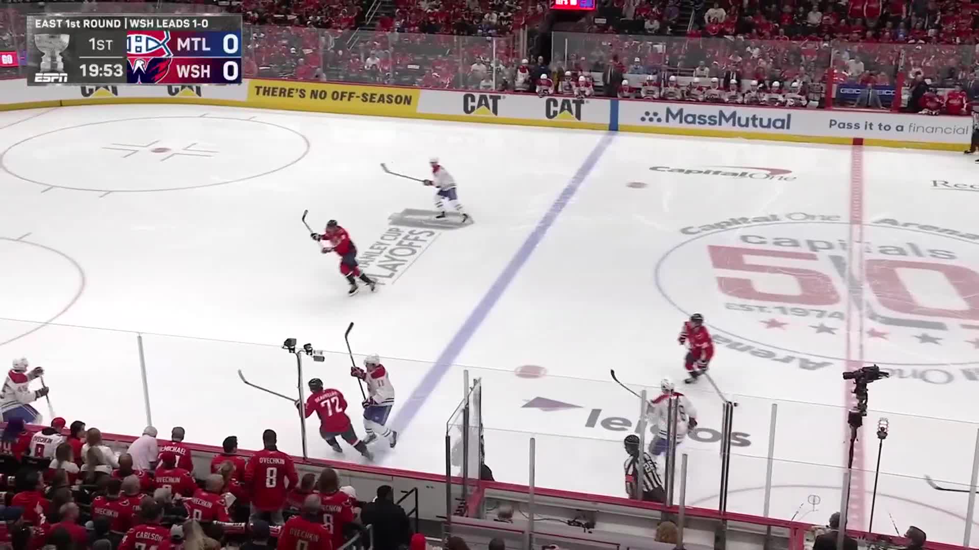 The Capitals in red are skating hard toward the puck, while the Canadiens in blue try to keep them at bay.  The score is tied, and the clock is ticking down in the first period of this NHL playoff game.
