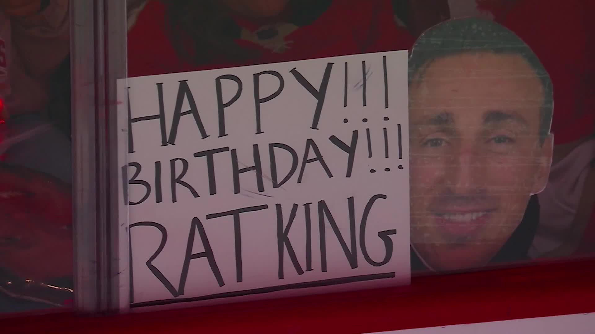 A handmade sign with "Happy Birthday!!! Rat King" is held up, next to a cardboard cutout of a smiling man. The image is framed, likely from a broadcast on NHL Network.
