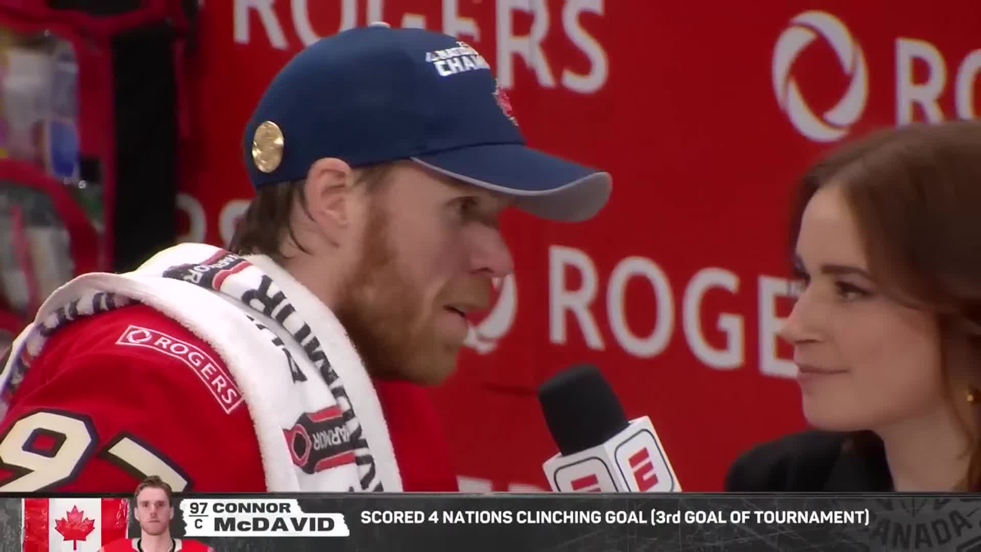 A hockey player, wearing a hat and jersey, is being interviewed by a woman on the NHL Network. The player has a towel around his neck and is speaking into a microphone.

