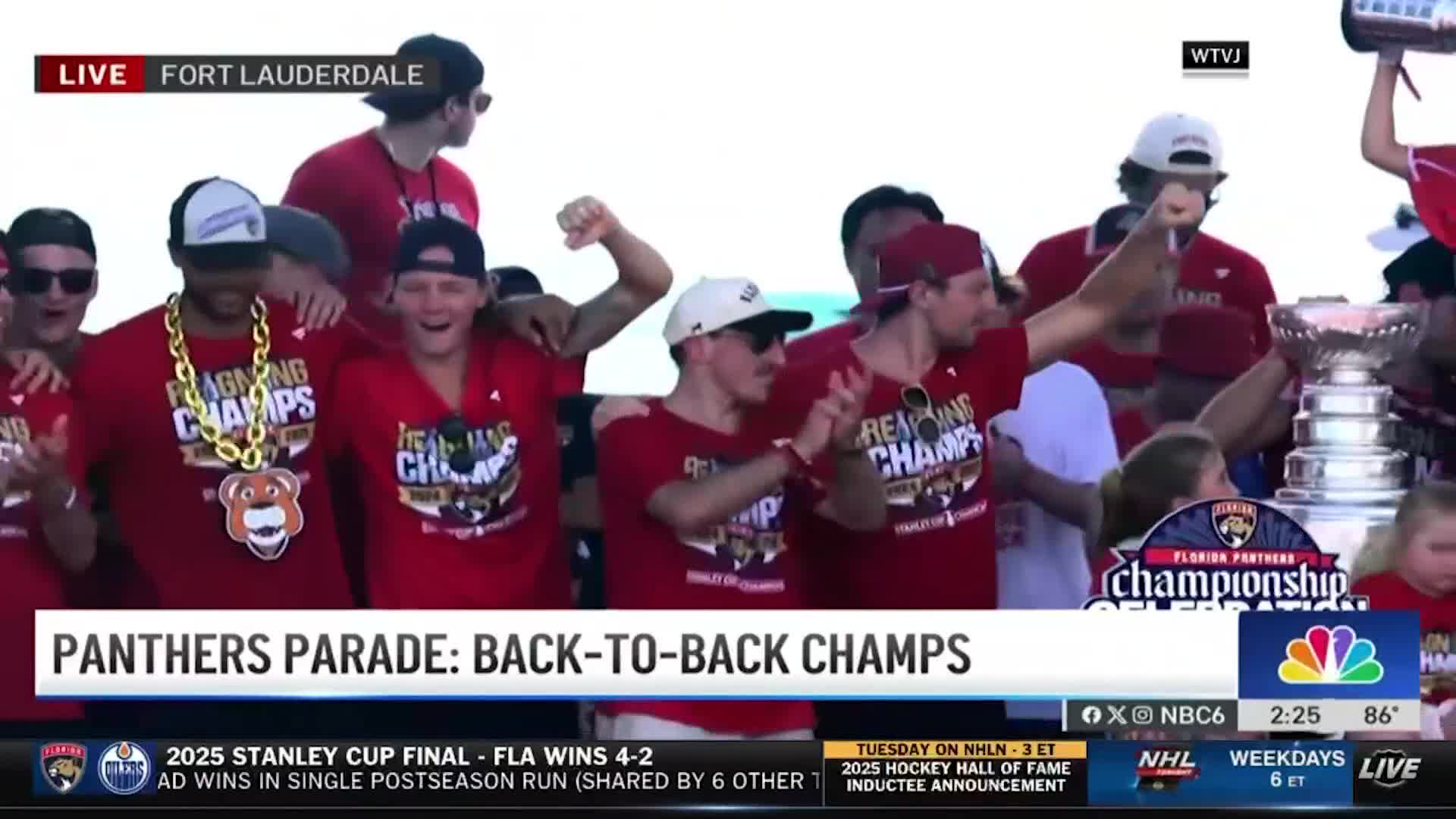 The Florida Panthers are celebrating, a group of them crowded together, hoisting the Stanley Cup. Some are wearing championship shirts and grinning, while others hold up their arms in triumph.
