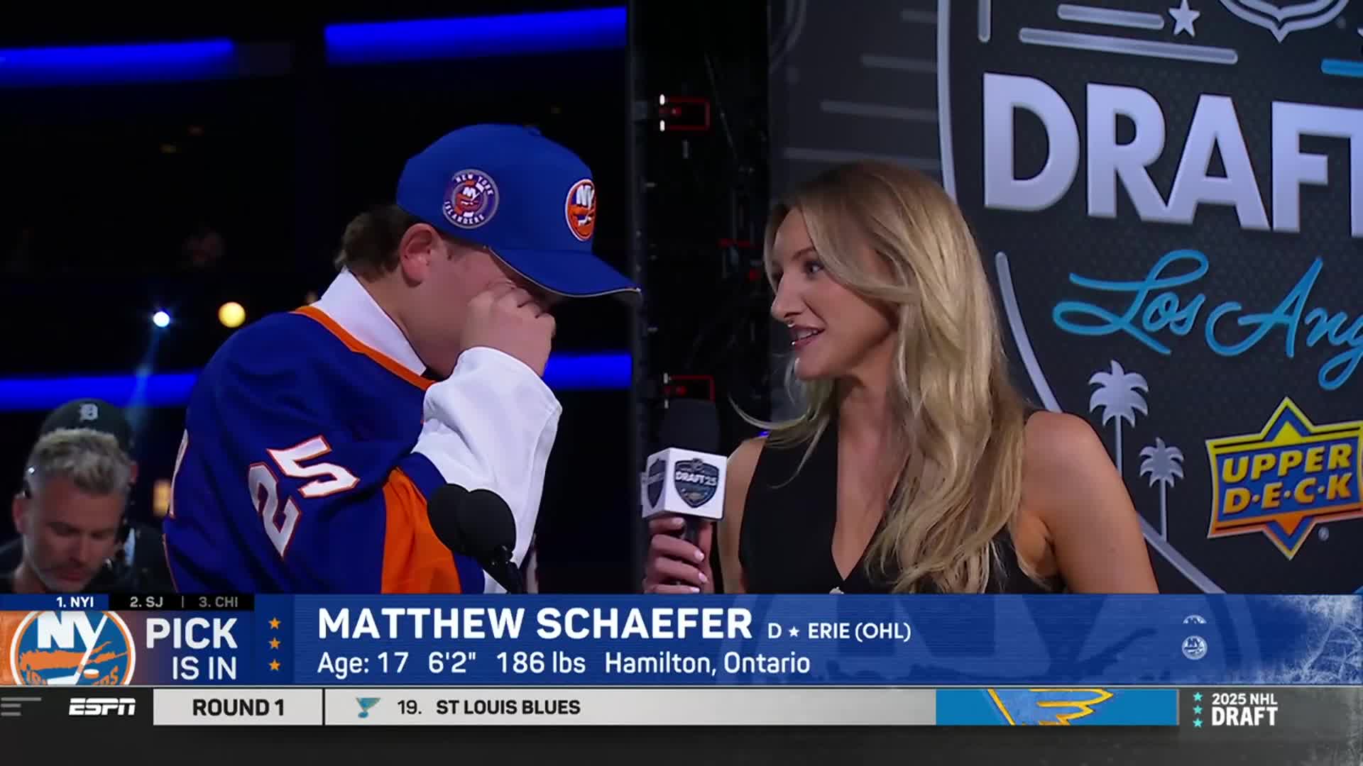 A young man, wearing an Islanders jersey and cap, wipes his eyes as a reporter holds a microphone. The NHL Draft logo is visible in the background, and the ESPN graphic identifies him as Matthew Schaefer.

