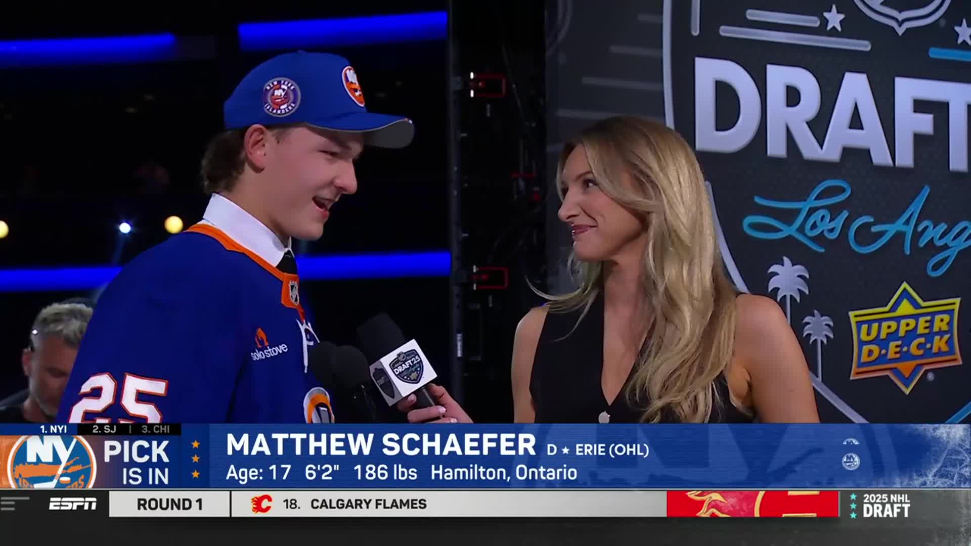 A young man in an Islanders jersey grins while being interviewed on the NHL Network. The woman holding the microphone listens intently, her eyes fixed on him.
