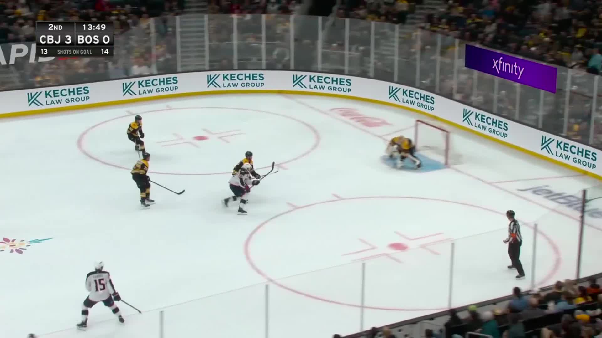 The puck carrier in white skates towards the net, pursued by a player in black and gold. The goalie, in yellow, is set up, ready to defend.
