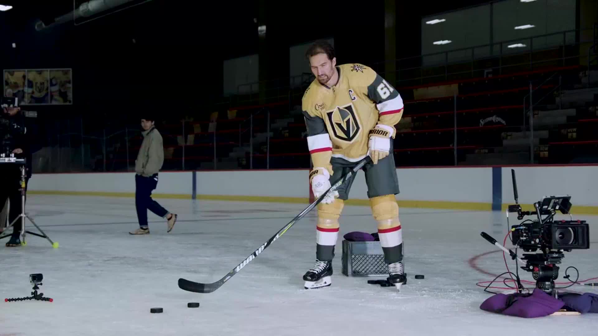 A hockey player in a Vegas Golden Knights jersey prepares to take a shot on the ice. Cameras are set up around him, ready to capture the action for NHL Network.