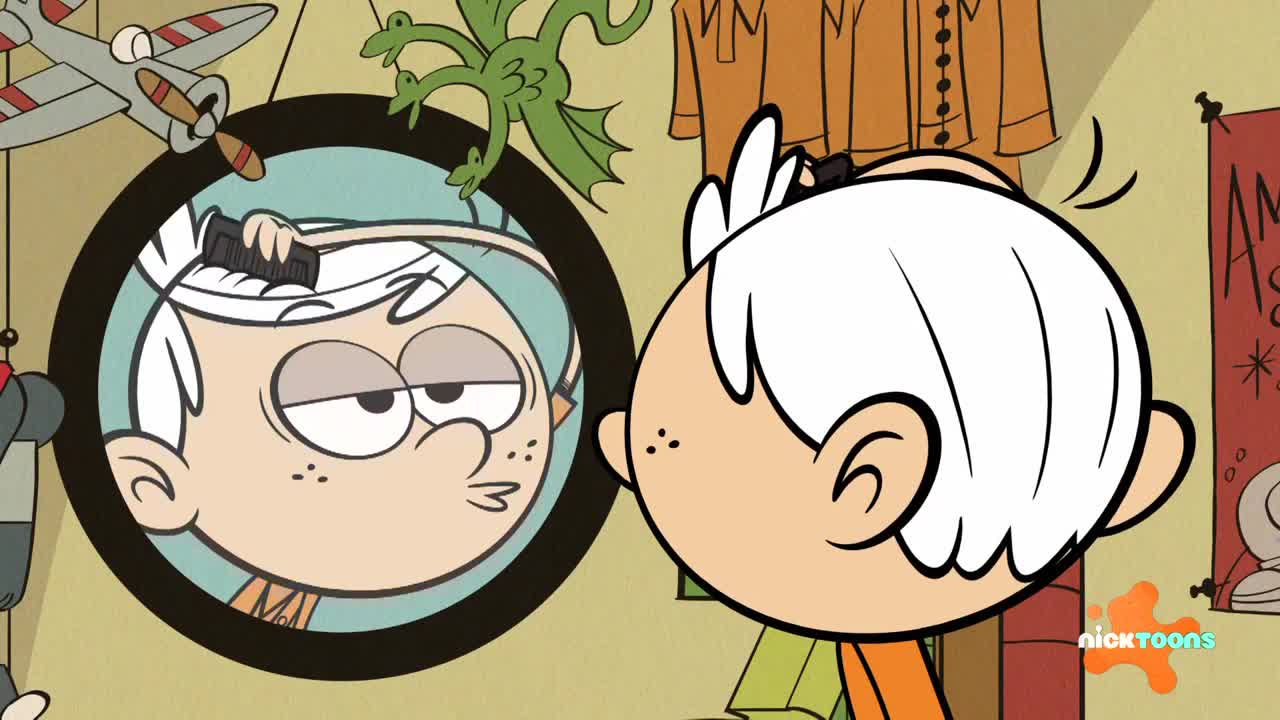 A boy with white hair combs his reflection in the mirror, puckering his lips. Behind him, a toy airplane hangs from the ceiling.