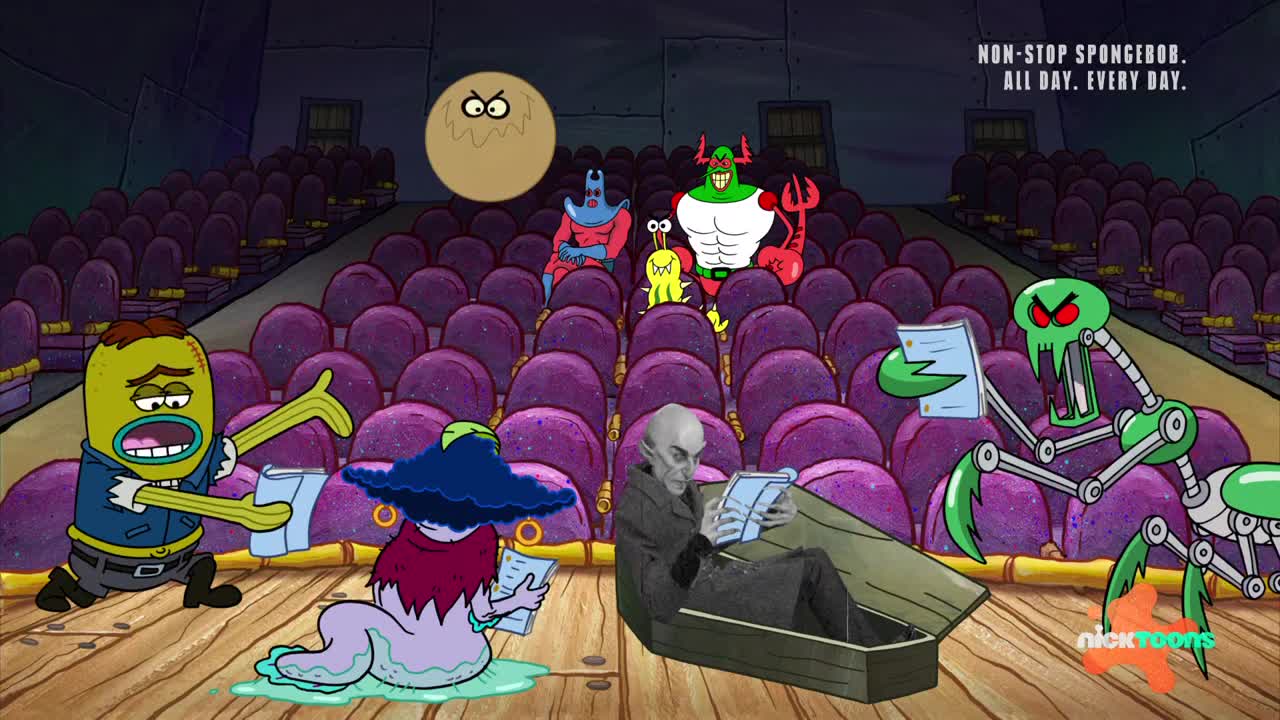 A green, robotic creature with spider-like legs is reading a script, its mouth open in a shout. Nearby, a pale figure reclines in a coffin, also engrossed in a paper.