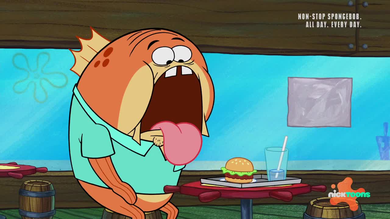 A large, orange fish with its mouth wide open is about to eat a burger. The fish's tongue is hanging out, ready to grab the food.