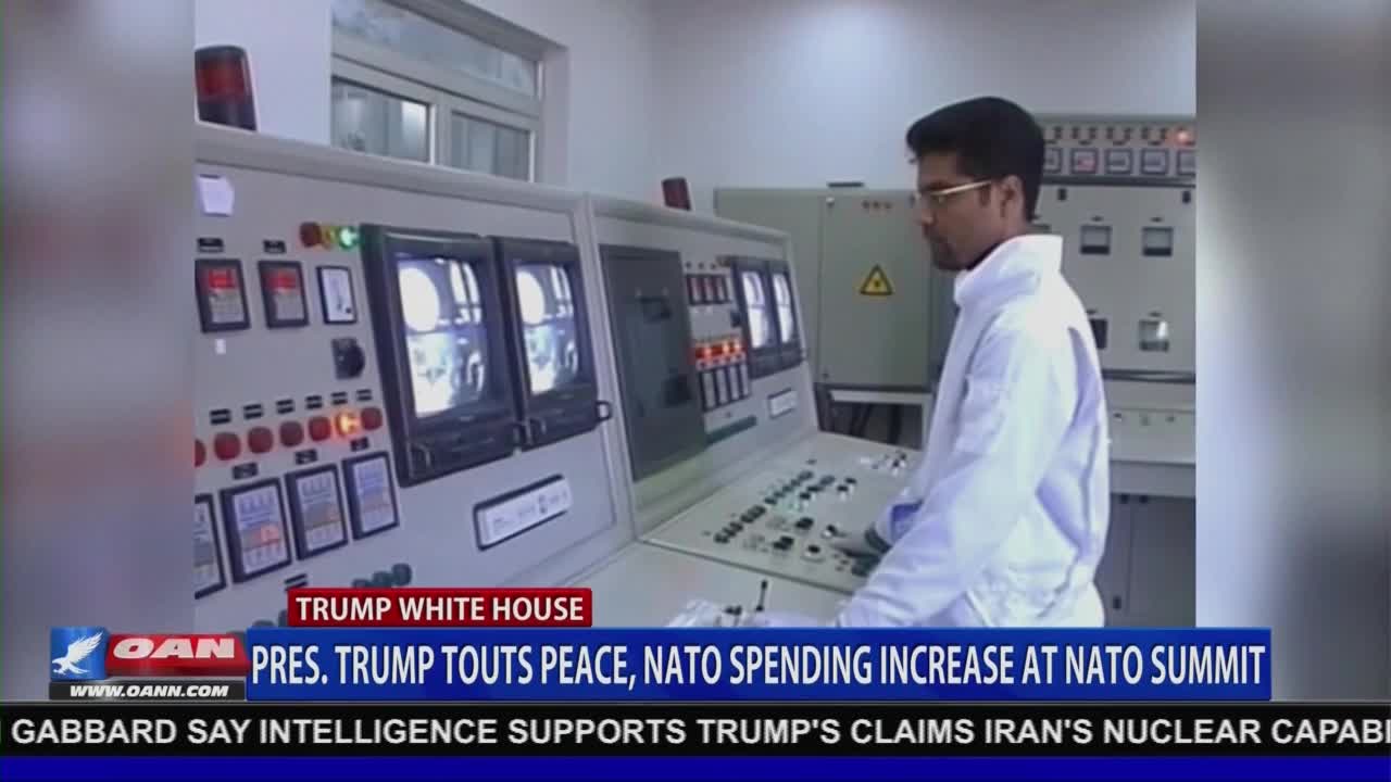 A man in a white coat stands before a control panel, his attention focused on the screens and dials. The bottom of the screen displays a banner from One America News Network, reporting on Trump and NATO.

