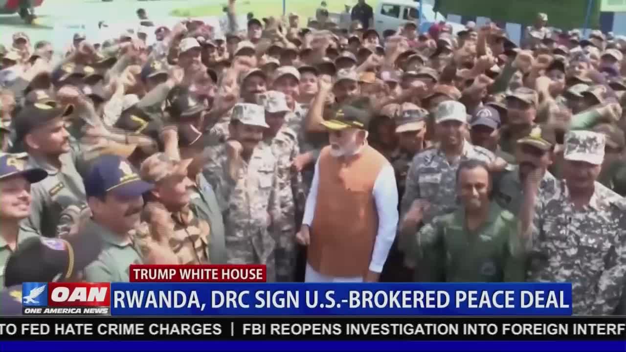 A crowd of uniformed individuals surrounds a man in an orange vest, many raising their arms in the air. The broadcast from One America News Network reports on a U.S.-brokered peace deal.
